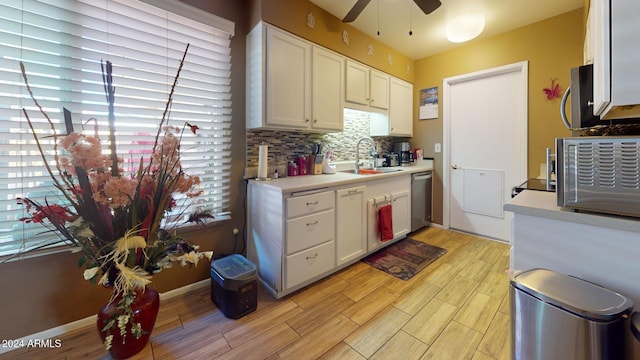 kitchen with light hardwood / wood-style floors, white cabinetry, sink, and backsplash