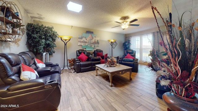 living room featuring light hardwood / wood-style flooring, a textured ceiling, and ceiling fan