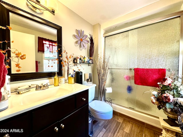 bathroom featuring hardwood / wood-style floors, vanity, toilet, and an enclosed shower