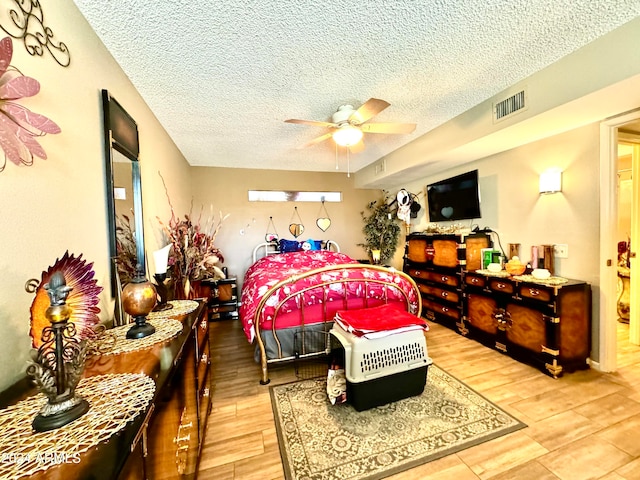 bedroom with hardwood / wood-style flooring, ceiling fan, and a textured ceiling