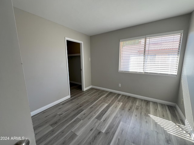 unfurnished bedroom with a closet, light hardwood / wood-style floors, and a walk in closet