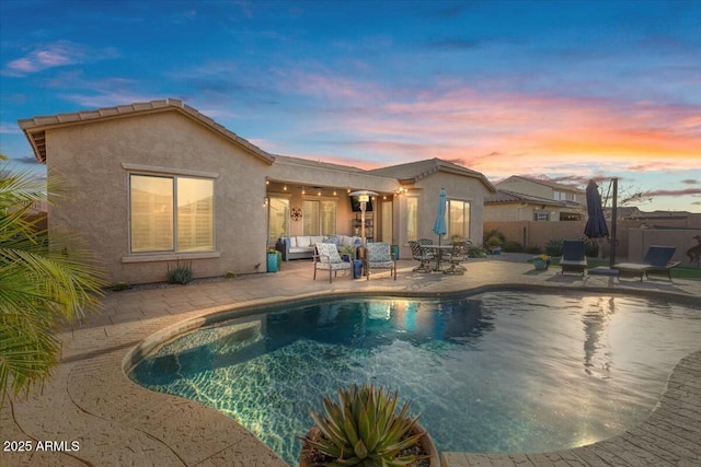 pool at dusk featuring an outdoor living space and a patio