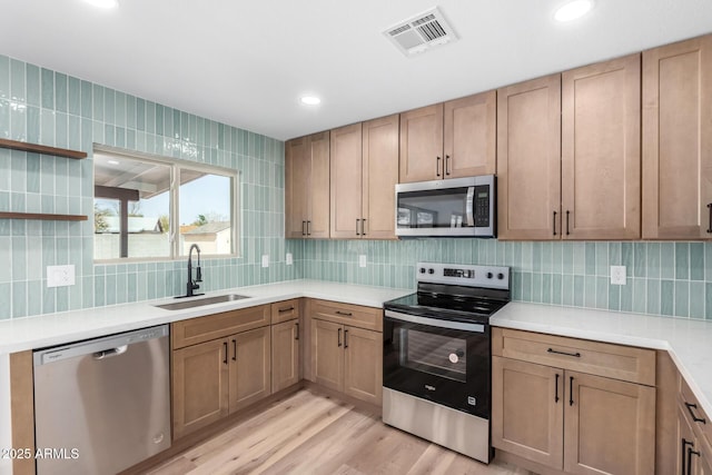 kitchen with visible vents, decorative backsplash, appliances with stainless steel finishes, light wood-type flooring, and a sink