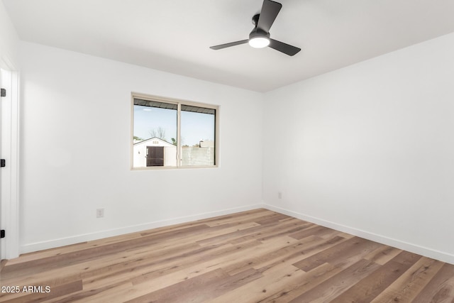 spare room featuring light wood finished floors, a ceiling fan, and baseboards