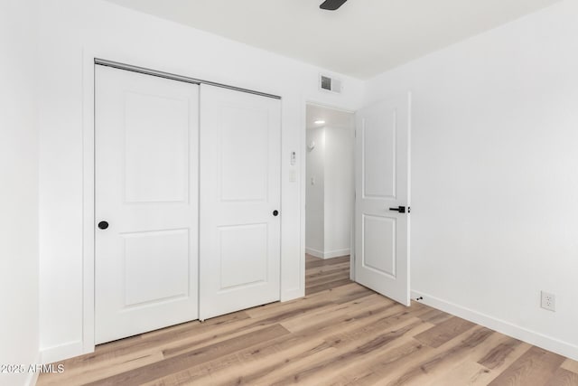 unfurnished bedroom with light wood-style floors, baseboards, visible vents, and a closet