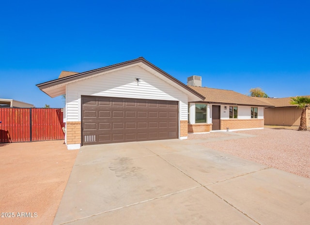 ranch-style house featuring a garage, concrete driveway, brick siding, and fence