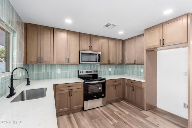 kitchen featuring visible vents, light wood-style flooring, stainless steel appliances, light countertops, and a sink