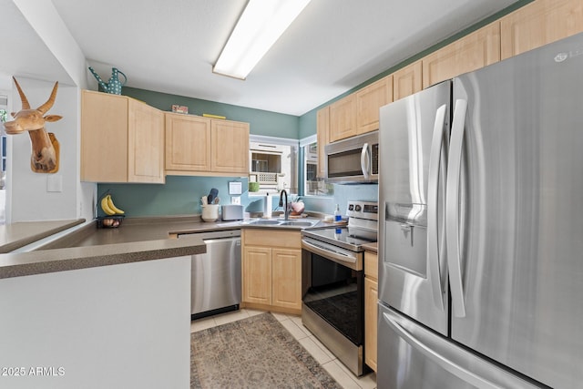 kitchen featuring a sink, stainless steel appliances, light tile patterned floors, and light brown cabinets