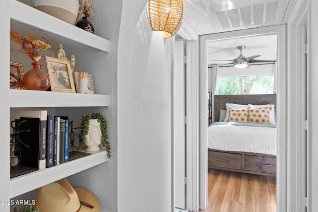 hallway featuring a textured wall, wood finished floors, and visible vents