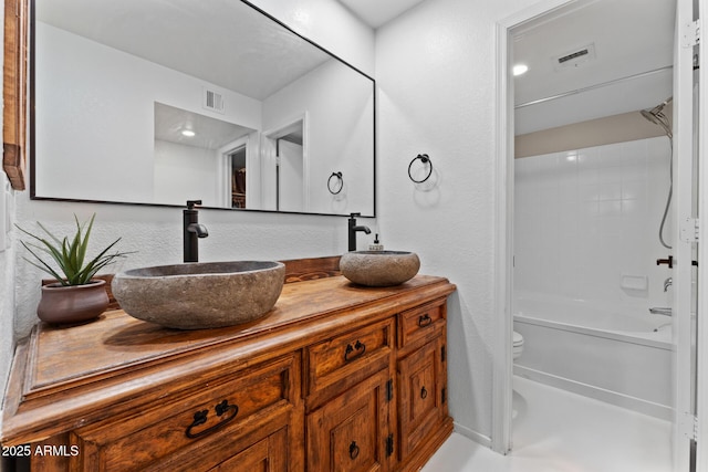 full bath with visible vents, double vanity, a sink, and toilet