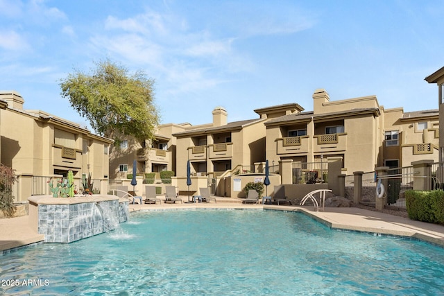 community pool with a patio, fence, and a residential view