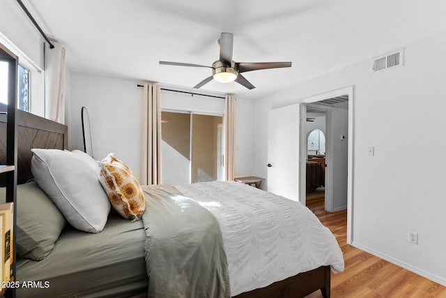 bedroom featuring light wood-style floors, baseboards, visible vents, and a ceiling fan