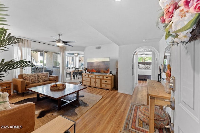 living area featuring ceiling fan, light wood finished floors, visible vents, and a healthy amount of sunlight