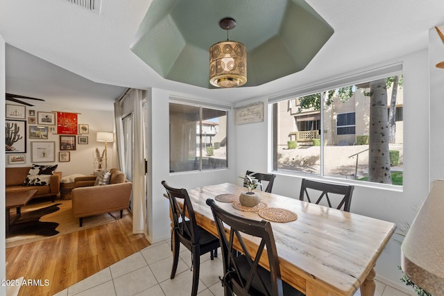 dining space featuring tile patterned flooring and a raised ceiling