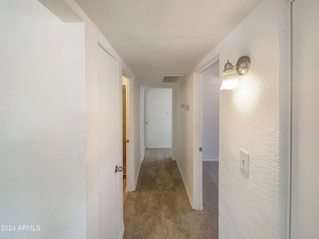 corridor featuring light carpet and a textured ceiling