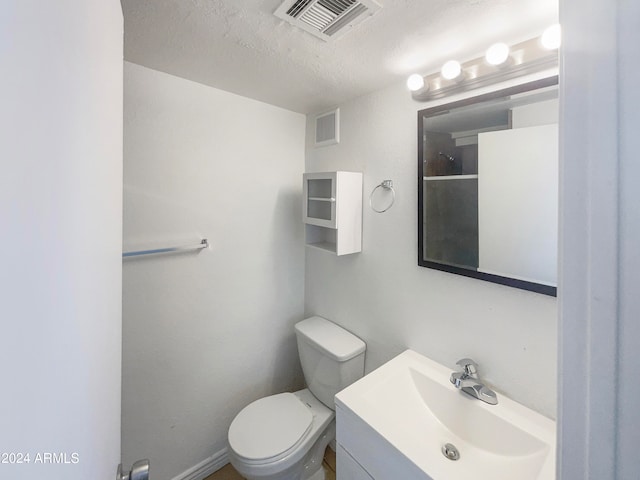 bathroom featuring vanity, a textured ceiling, and toilet