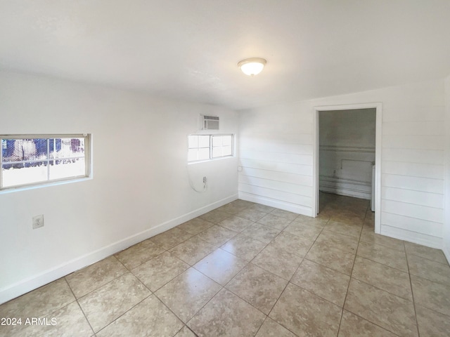 empty room featuring light tile patterned floors, lofted ceiling, and a healthy amount of sunlight