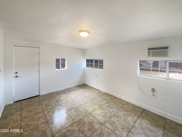 tiled empty room featuring an AC wall unit