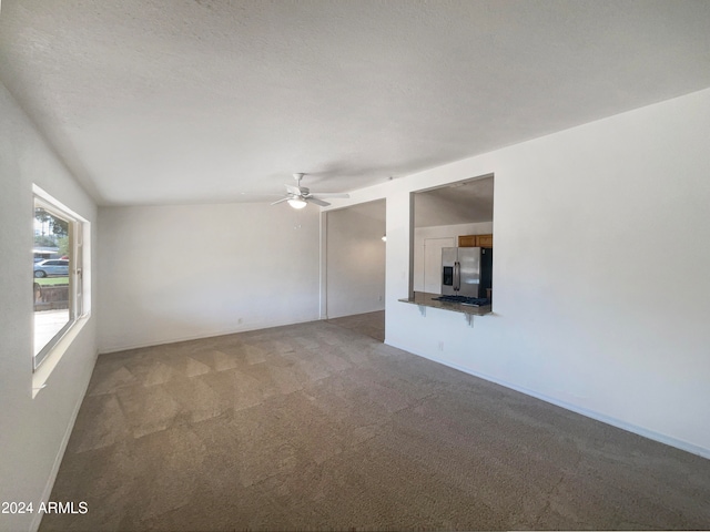 unfurnished living room with a textured ceiling, carpet floors, ceiling fan, and lofted ceiling