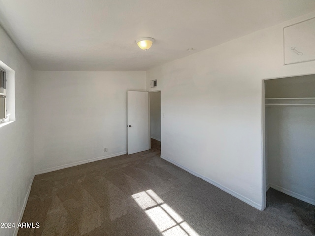 unfurnished bedroom with a closet and dark carpet