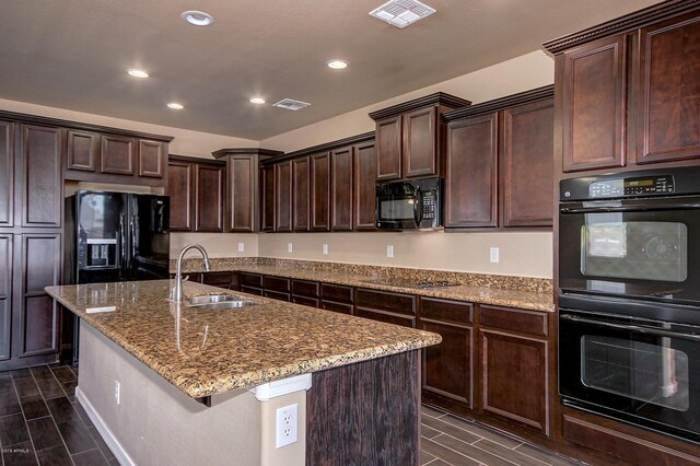 kitchen featuring dark brown cabinets, sink, a kitchen island with sink, and black appliances