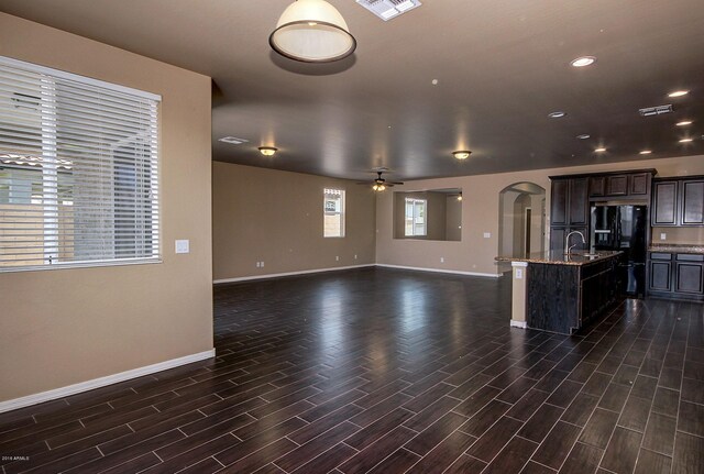 kitchen featuring sink, ceiling fan, an island with sink, black fridge with ice dispenser, and dark brown cabinetry