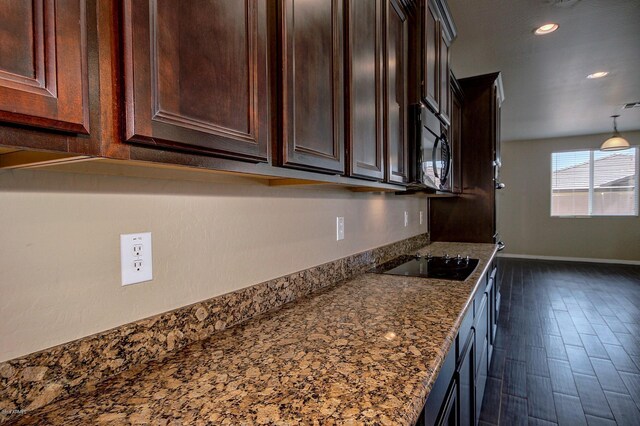 kitchen with dark wood-type flooring, black appliances, and stone countertops