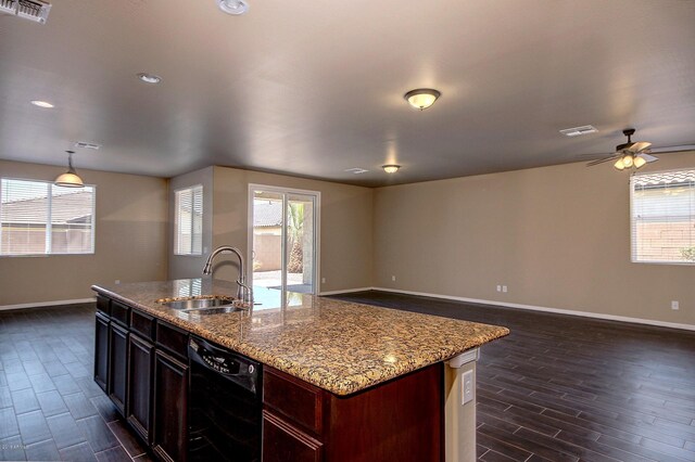 kitchen with light stone counters, a kitchen island with sink, sink, dishwasher, and hanging light fixtures