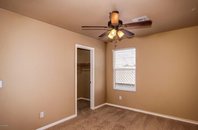 unfurnished bedroom featuring ceiling fan, light colored carpet, a walk in closet, and a closet