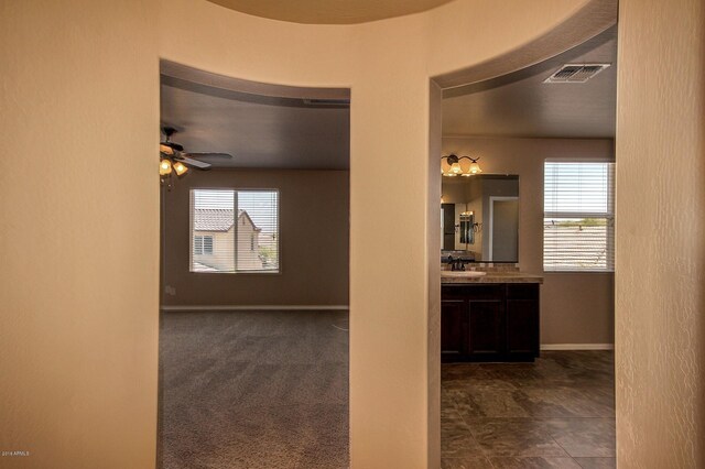 hallway featuring dark colored carpet and sink