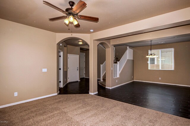 carpeted empty room featuring ceiling fan with notable chandelier