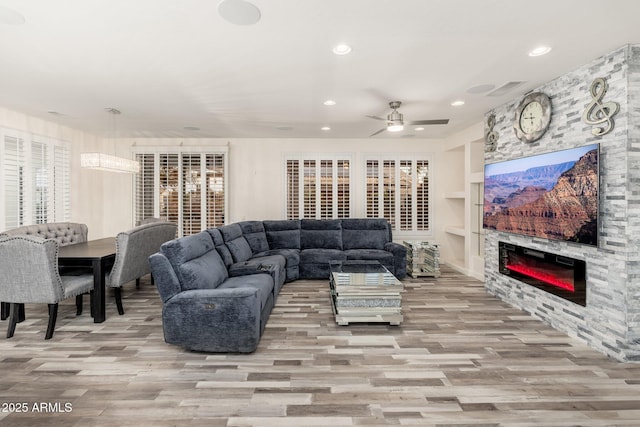15583 W Big Sky Dr, Surprise, AZ 85374 - living room with ceiling fan, a stone fireplace, light wood-type flooring, and built in shelves