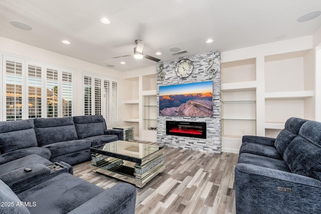 15583 W Big Sky Dr, Surprise, AZ 85374 - living room featuring built in shelves, ceiling fan, a fireplace, and light hardwood / wood-style floors