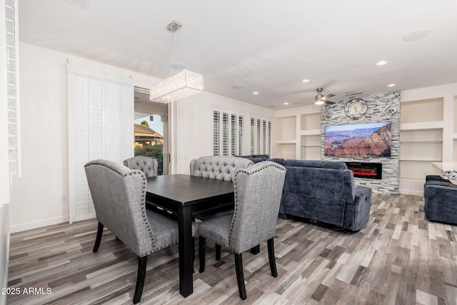 15583 W Big Sky Dr, Surprise, AZ 85374 - dining room with built in shelves, a fireplace, ceiling fan with notable chandelier, and hardwood / wood-style floors