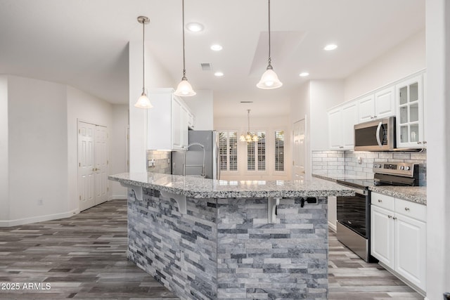 15583 W Big Sky Dr, Surprise, AZ 85374 - kitchen featuring backsplash, stainless steel appliances, a kitchen bar, and white cabinets