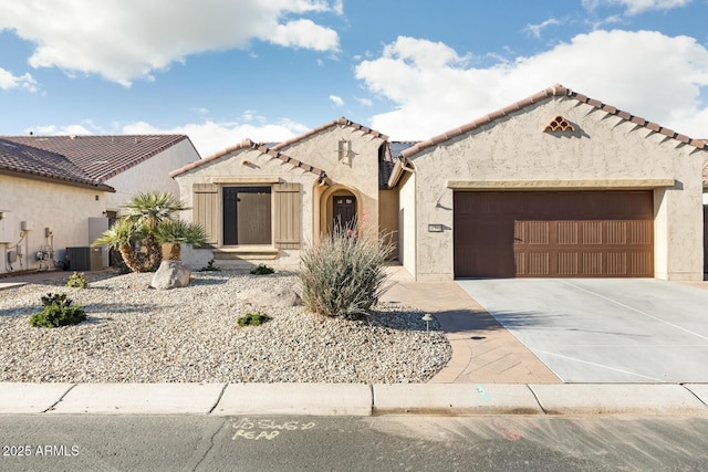 view of front facade featuring stucco siding, central AC, a garage, driveway, and a tiled roof