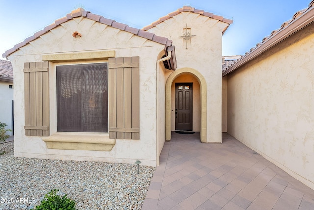 property entrance with a tile roof and stucco siding