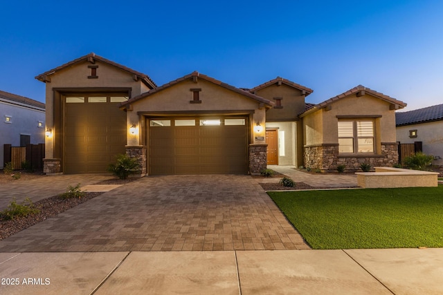 craftsman-style house with stucco siding, stone siding, decorative driveway, and an attached garage