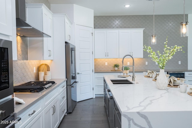 kitchen with a sink, wall chimney exhaust hood, white cabinets, and stainless steel appliances