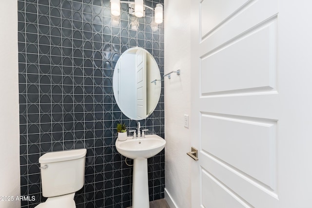 bathroom with toilet and tile walls
