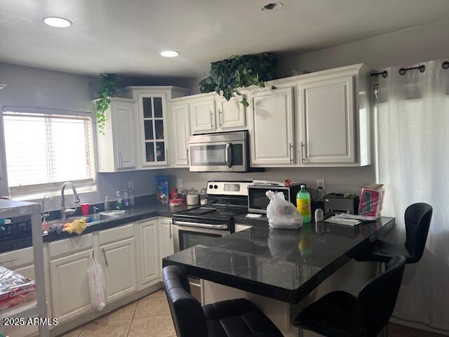 6128 W Palmaire Ave, Glendale, AZ 85301 - kitchen featuring appliances with stainless steel finishes, a sink, white cabinets, light tile patterned flooring, and recessed lighting