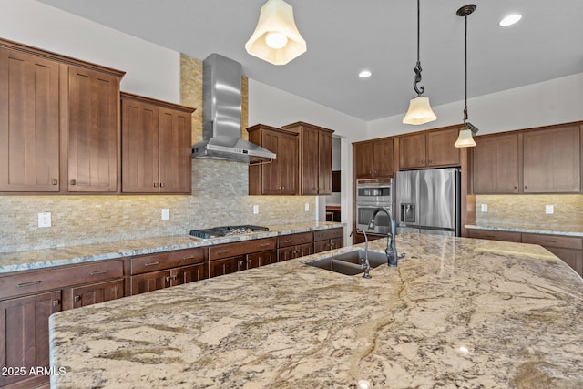 kitchen with appliances with stainless steel finishes, light stone countertops, wall chimney range hood, and a sink