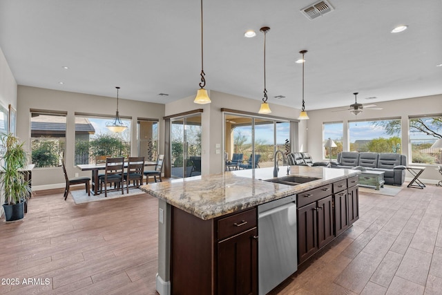 kitchen featuring light wood finished floors, visible vents, dark brown cabinetry, dishwasher, and a sink