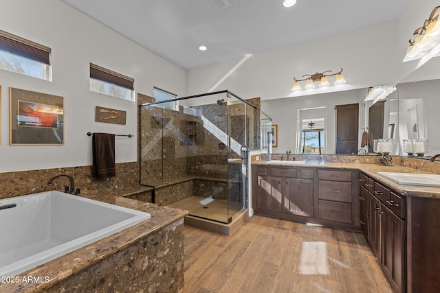 bathroom with double vanity, a bath, wood finished floors, and a sink