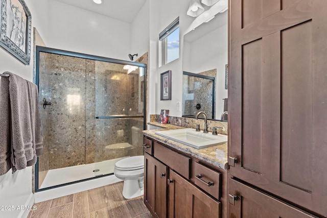 full bath featuring a stall shower, toilet, vanity, and wood finished floors