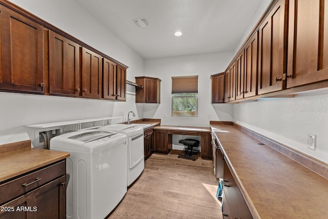 clothes washing area with visible vents, a sink, cabinet space, light wood-style floors, and separate washer and dryer