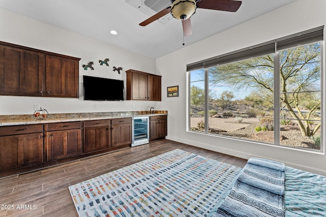 kitchen featuring a ceiling fan, dark wood-style floors, beverage cooler, baseboards, and dark brown cabinets