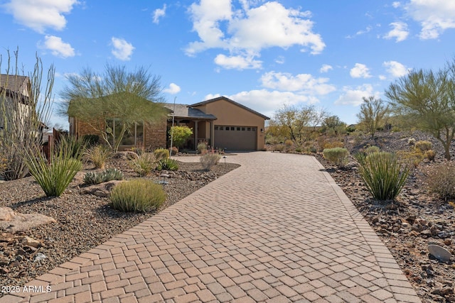 view of front of home with stucco siding, an attached garage, and decorative driveway