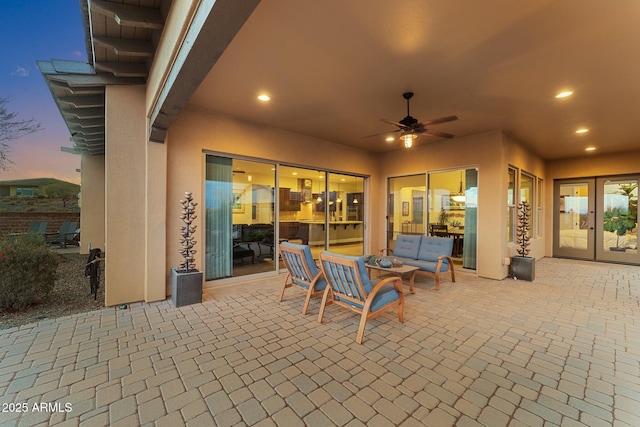 patio terrace at dusk featuring french doors, ceiling fan, and outdoor lounge area