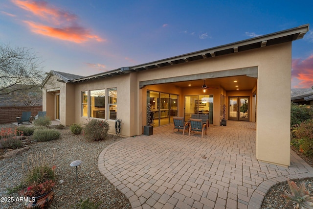 back of property at dusk featuring stucco siding and a patio area